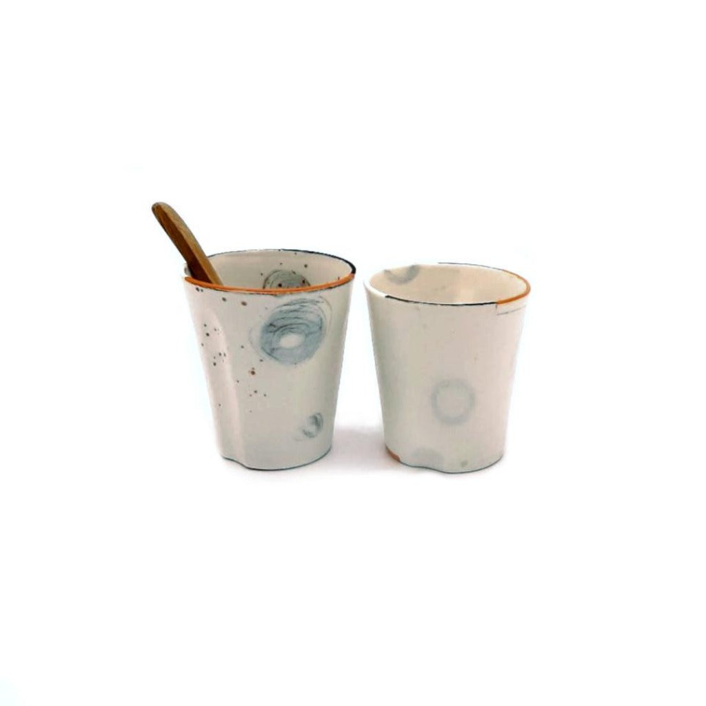 Kaolin - Guðný Magnúsdóttir - The Tea glasses or Espresso cups have each their own character in form and decoration. They are in white porcelain, hand painted individually  with orange and black lines on the edge and come in a set of two.
